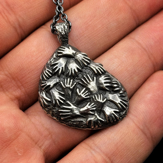 Silver pendant with hand patterns held in a hand