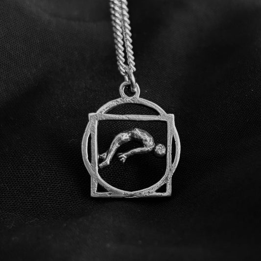 Silver pendant with a engraved design on a black background