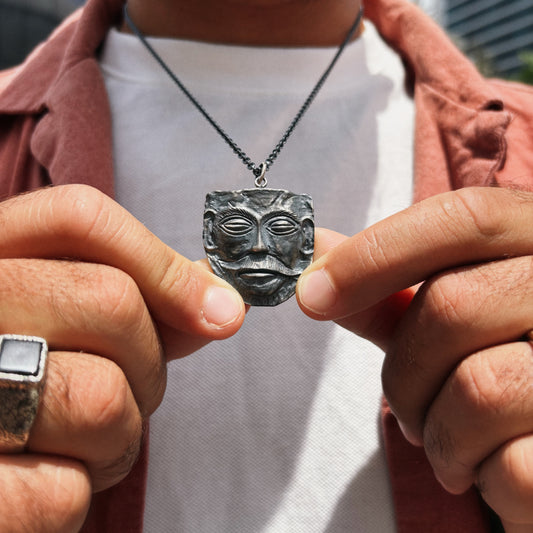 Person holding a necklace with a face-shaped pendant