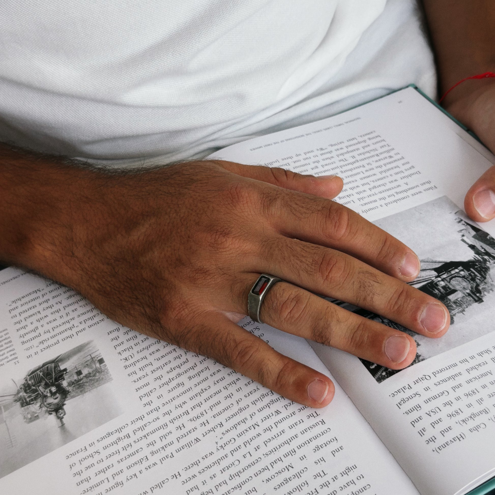 Person holding an open book with a close-up of a hand wearing a ring.