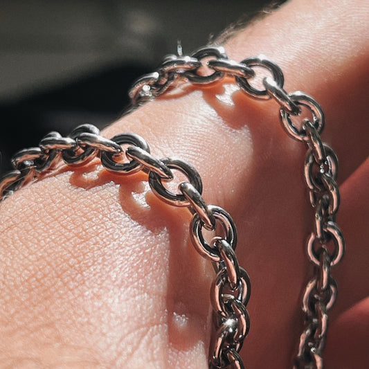 Close-up of a silver chain bracelet on a person's wrist with a blurred background.