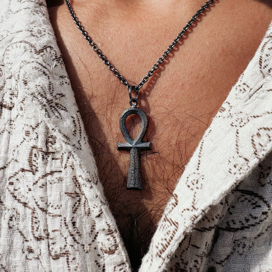 Necklace with an Ankh pendant worn by a person with a white lace garment.