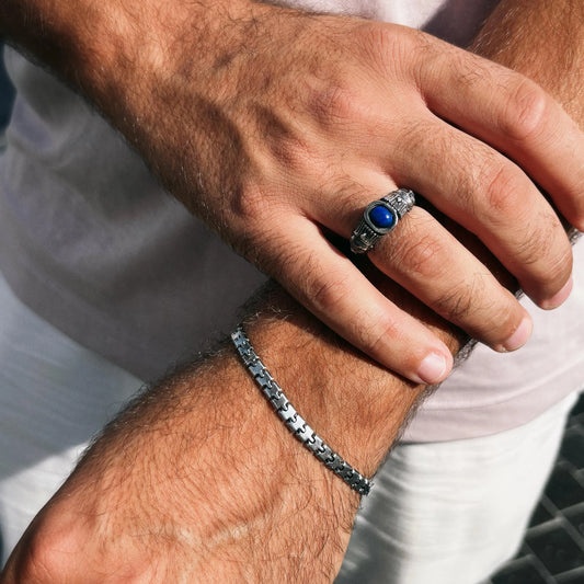 Close-up of a hand wearing a silver ring with a blue stone and a matching bracelet.
