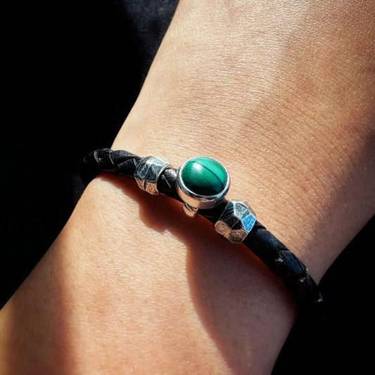 Bracelet with green stone and silver accents on a wrist against a dark background