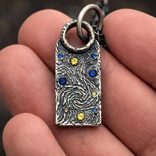 Silver pendant with embedded stones held in a hand