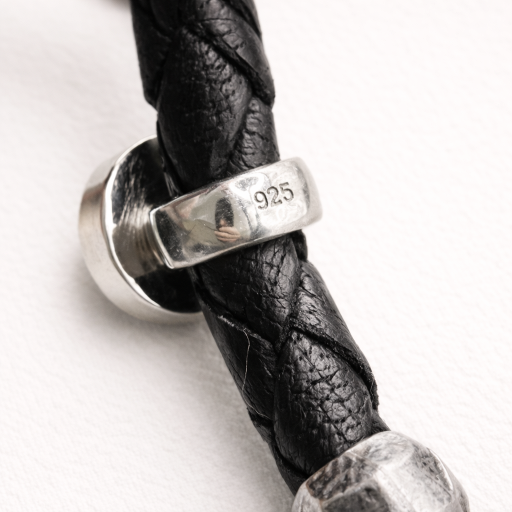 Black braided leather bracelet with a silver clasp on a white background