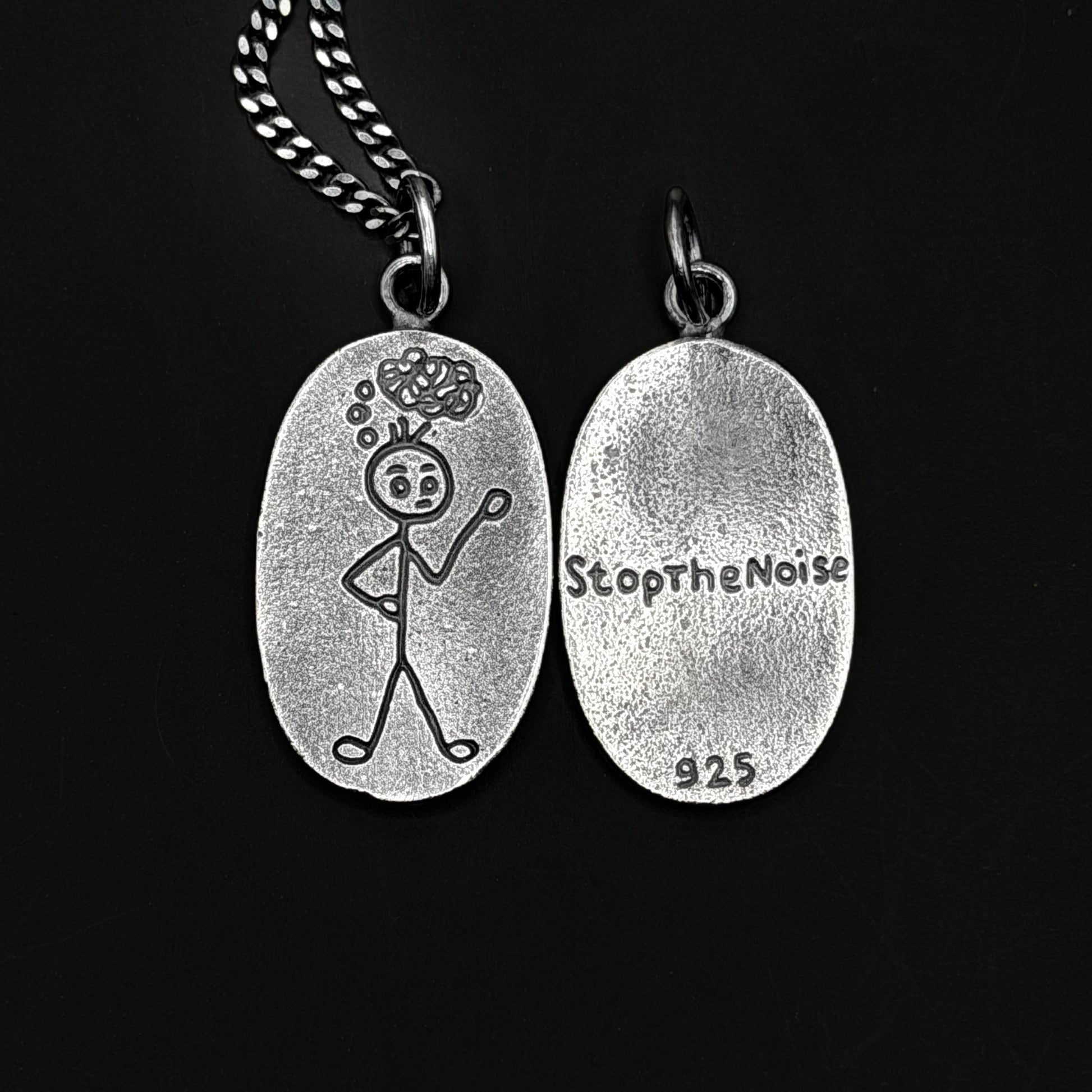 Silver pendant with a stick figure design and 'StopTheNoise' engraving on a black background
