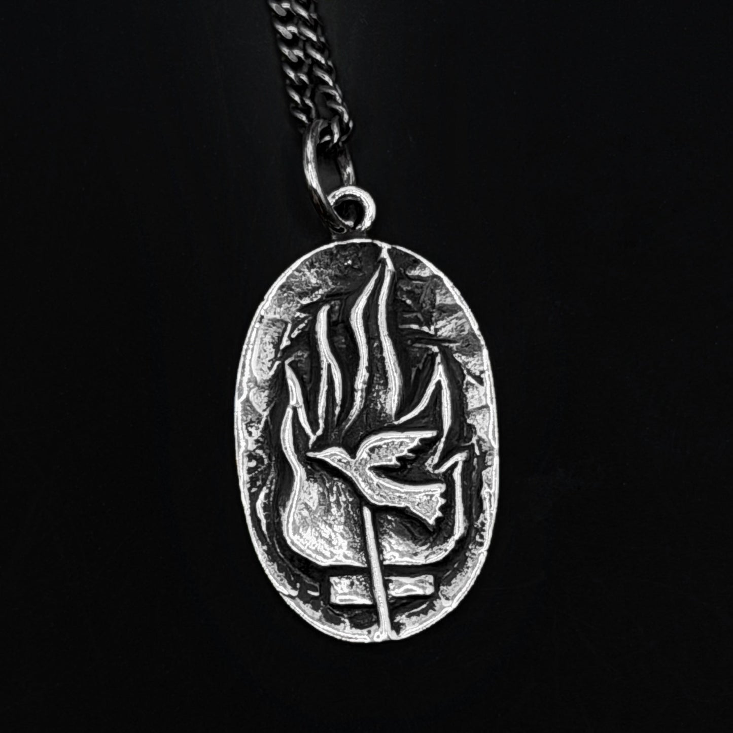 Silver pendant with leaf design on a black background