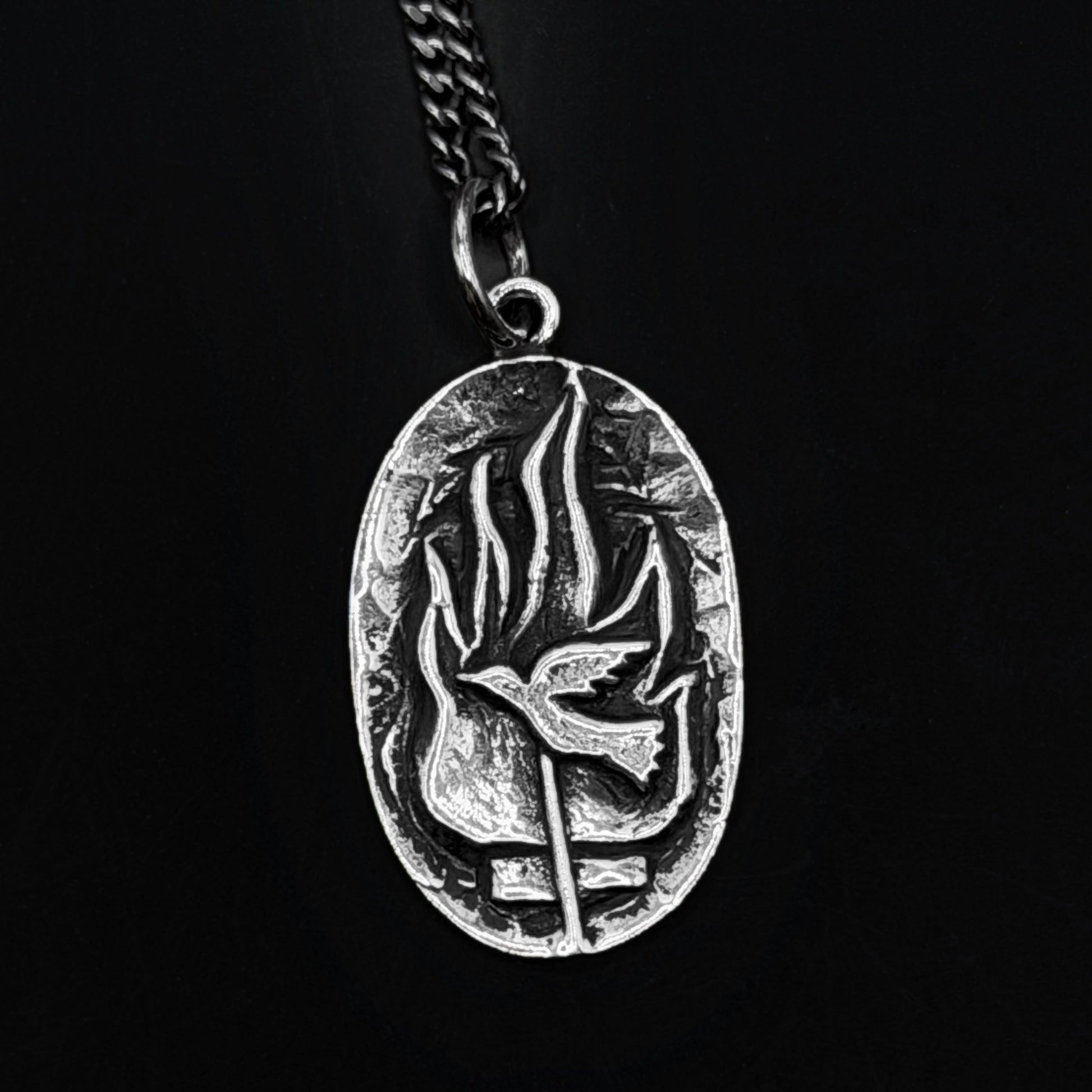 Silver pendant with leaf design on a black background