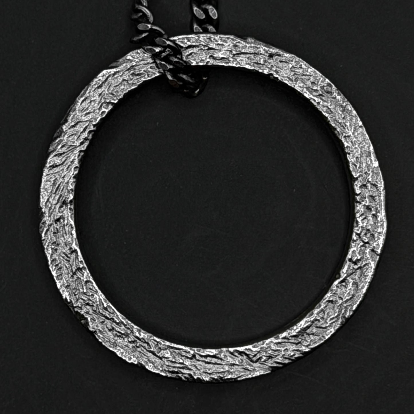 Silver circular pendant necklace on a black background
