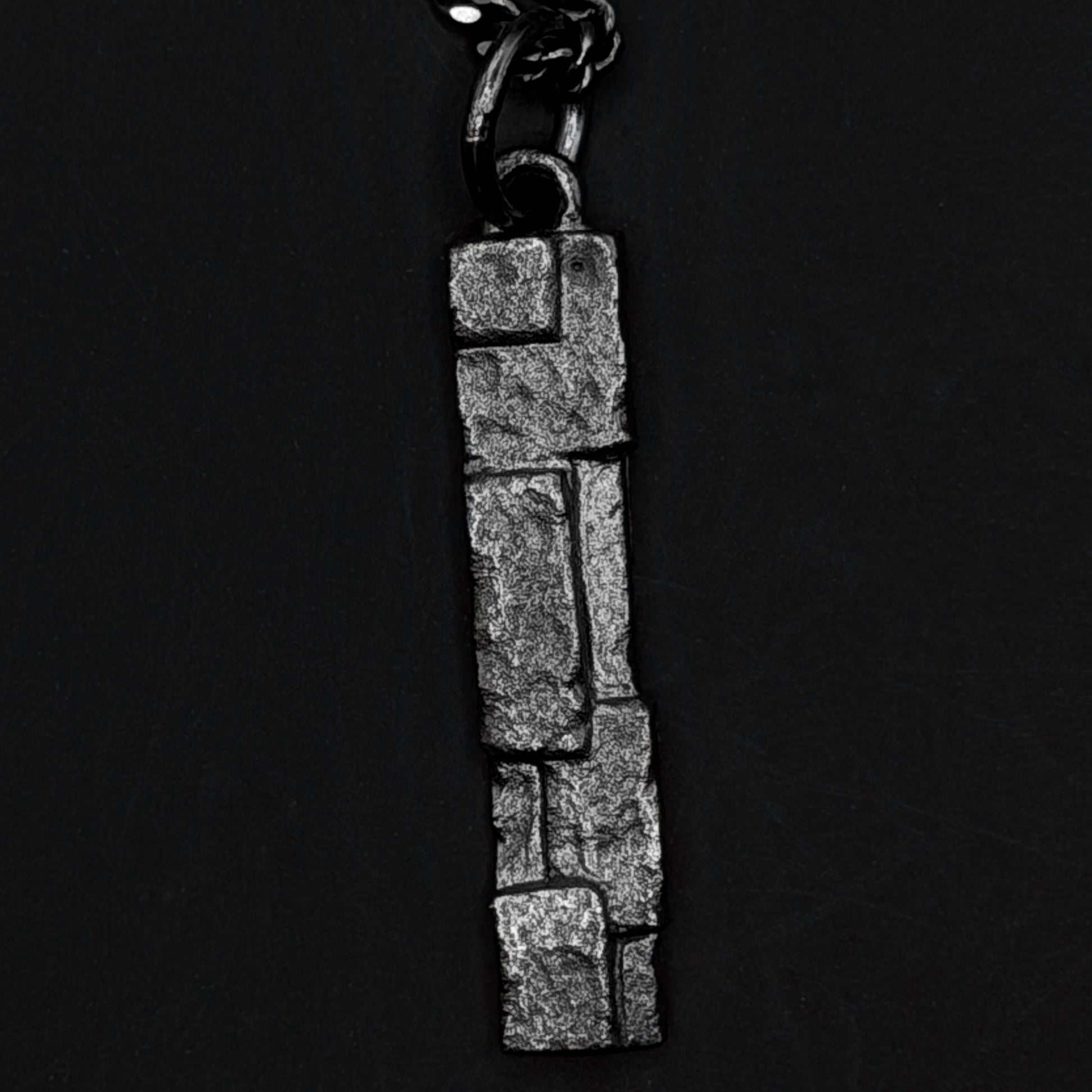 Silver pendant with stone-like texture on a black background