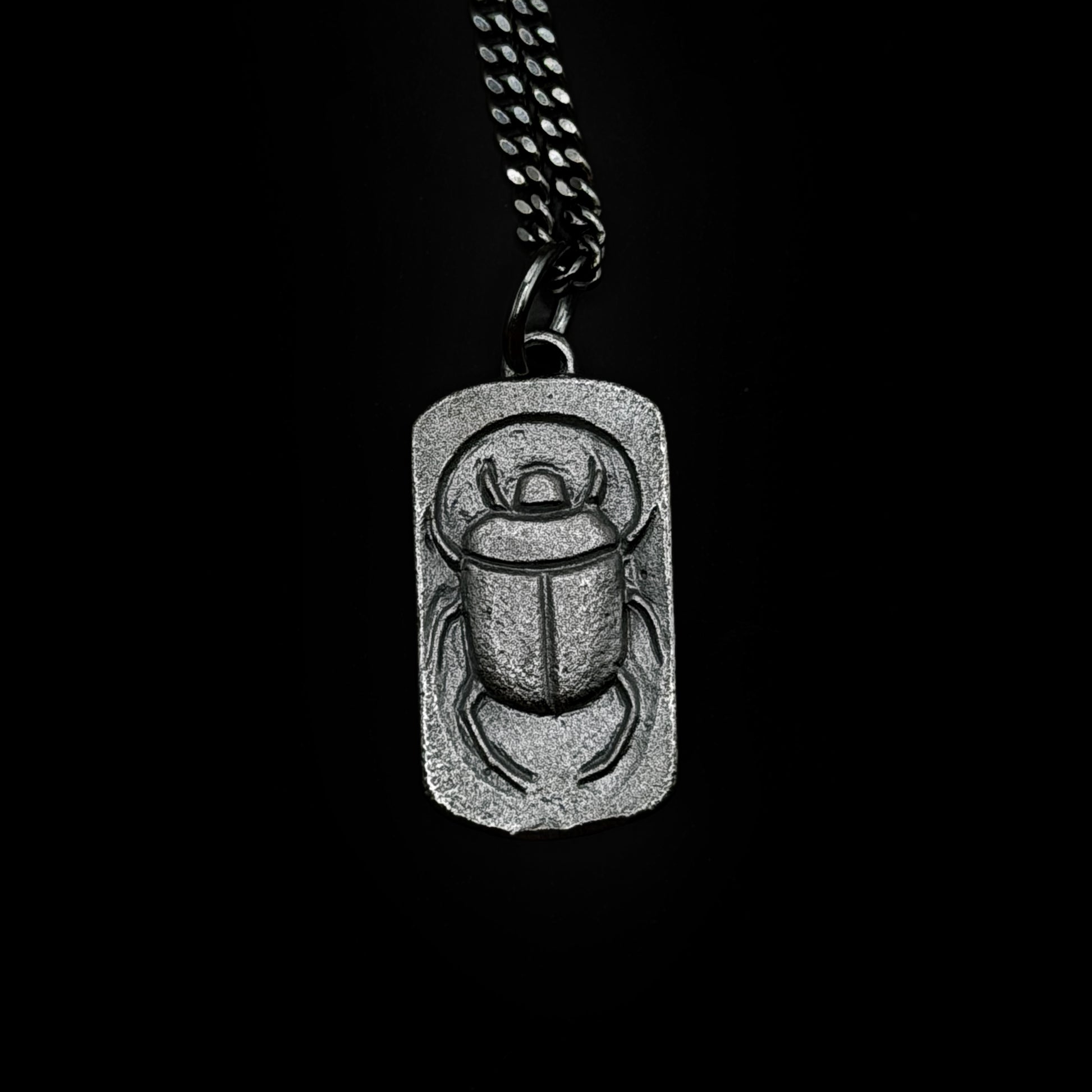 Silver scarab pendant necklace on a black background