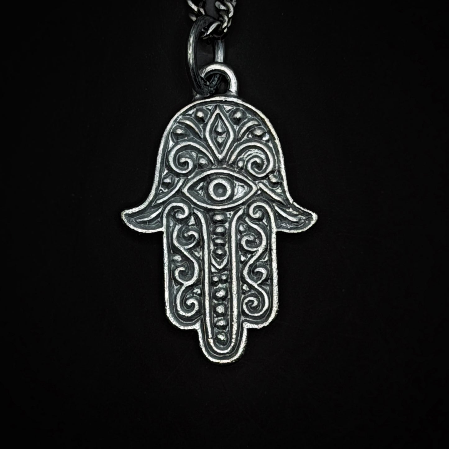Silver Hamsa hand pendant on a black background