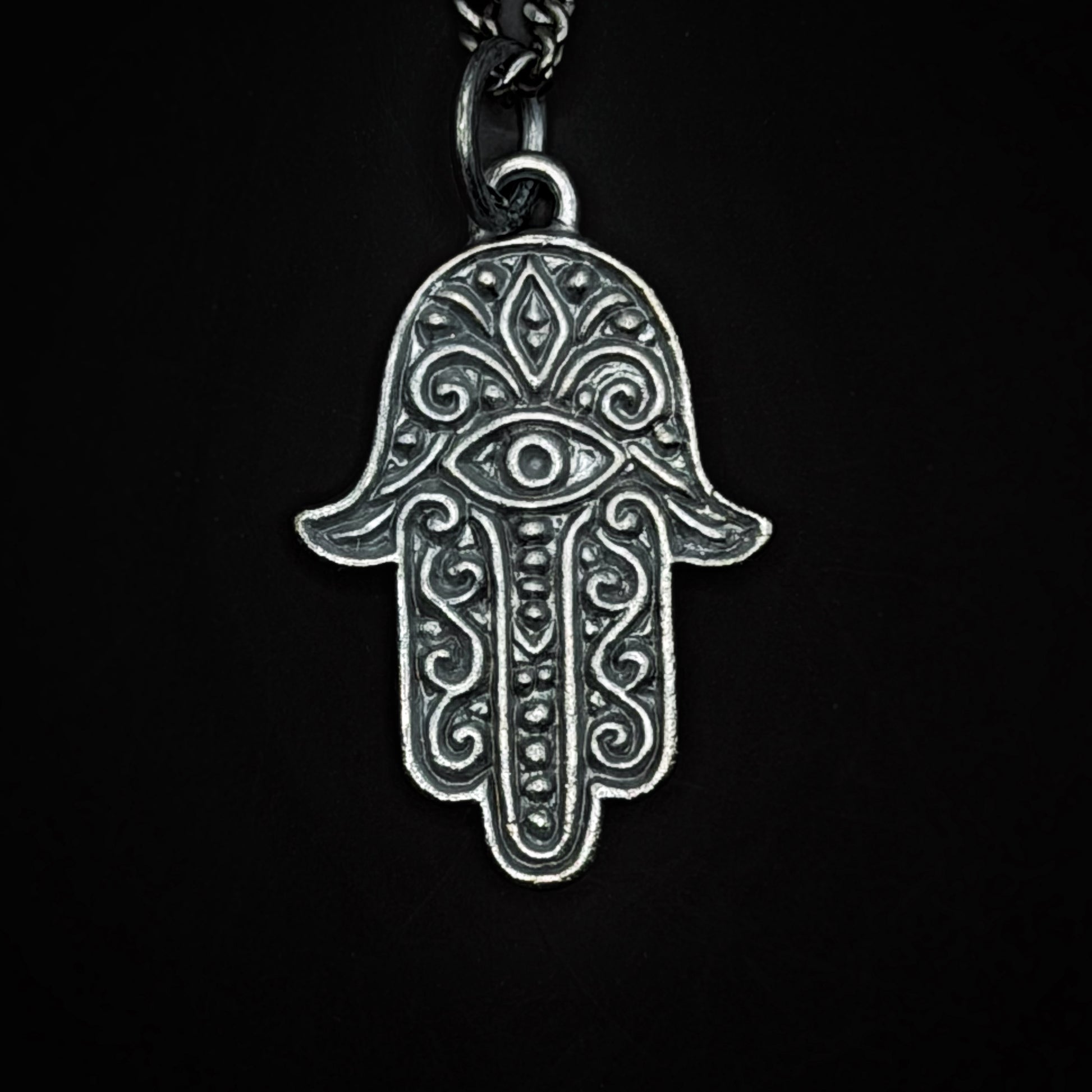 Silver Hamsa hand pendant on a black background