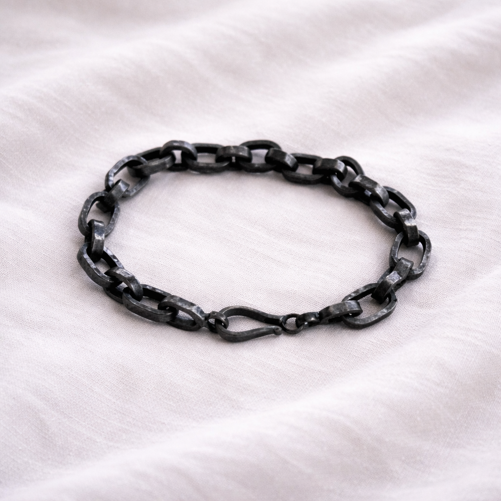 Black chain bracelet on a white fabric background