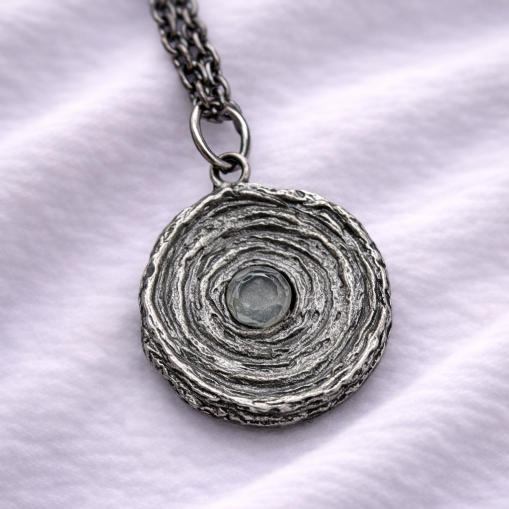 Silver necklace with a circular pendant on a white fabric background