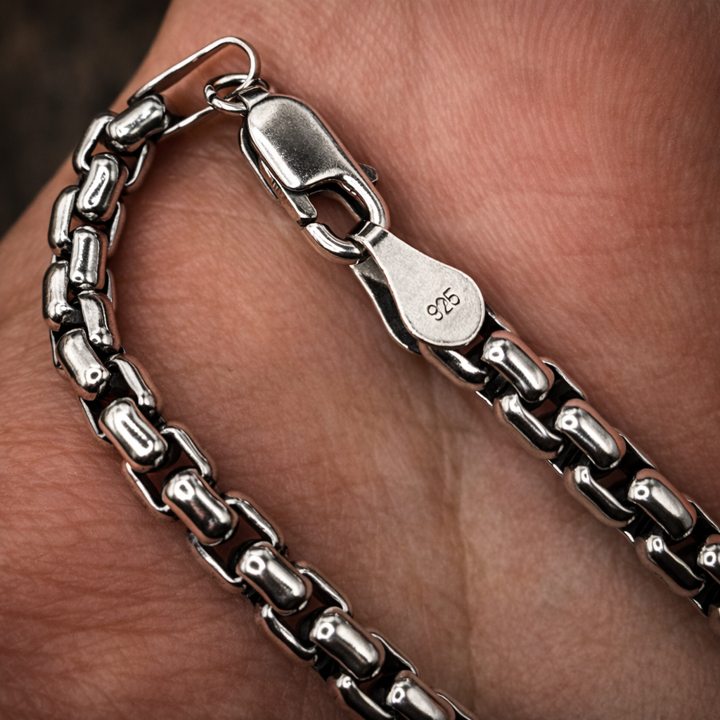 Silver chain bracelet on a wrist with a close-up view of the clasp.