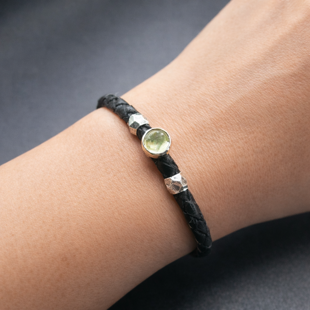 Black braided bracelet with a citrine gemstone on a wrist against a dark background