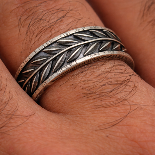 Close-up of a hand wearing a silver and bronze ring with intricate design.