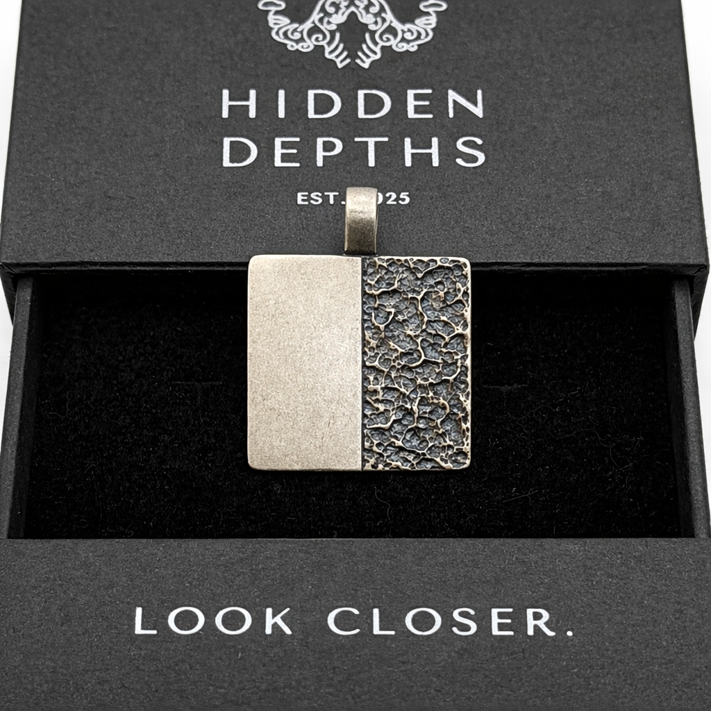 Two-tone pendant in a 'Hidden Depths' box with 'Look Closer.' text.