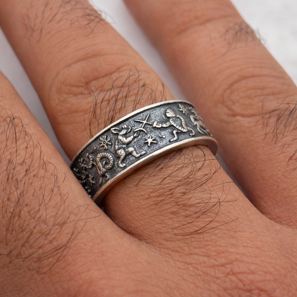 Silver ring with engraved designs on a person's finger