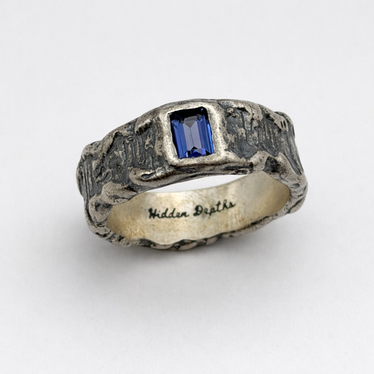 Silver ring with a blue gemstone on a white background