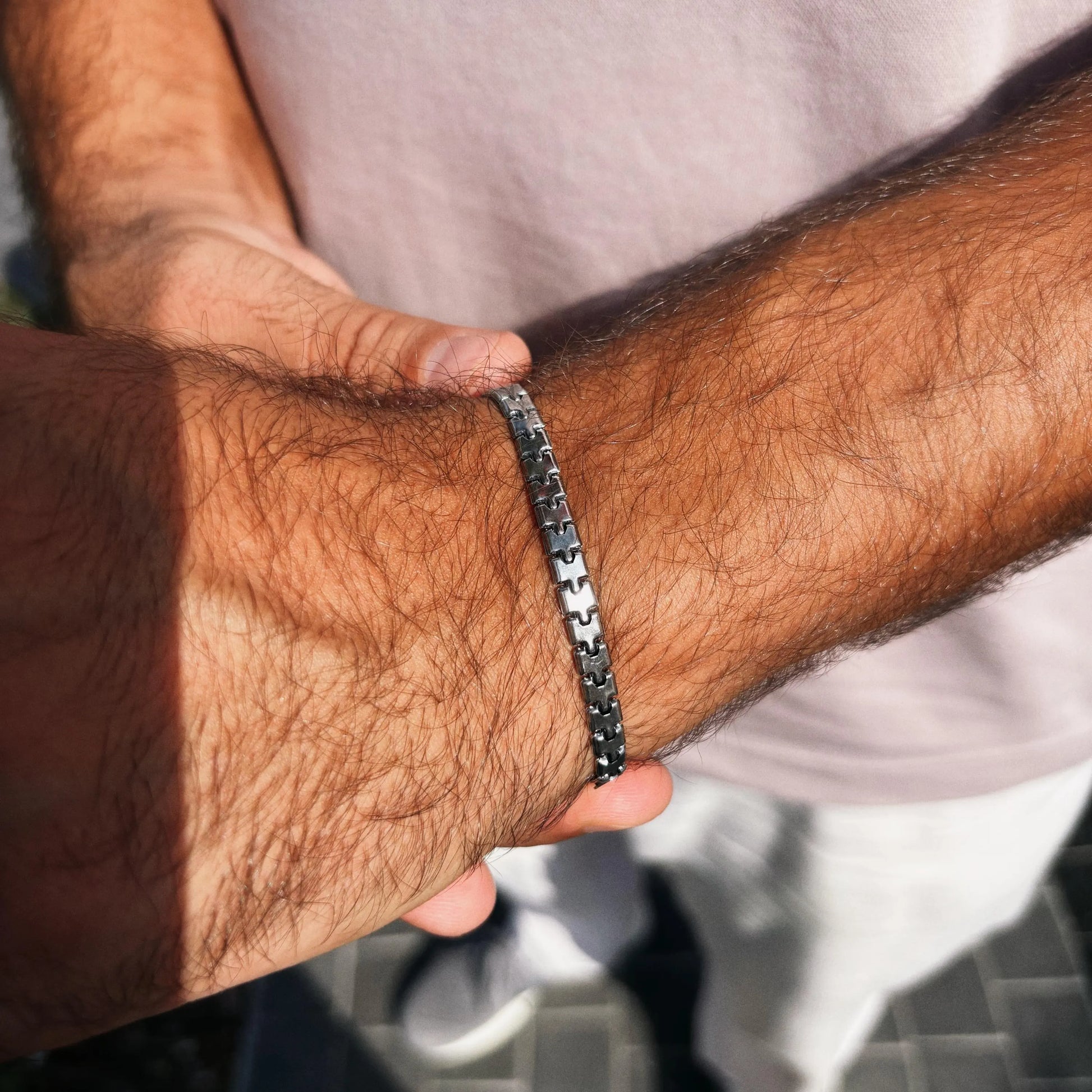 Close-up of a person's wrist wearing a silver bracelet with a blurred background