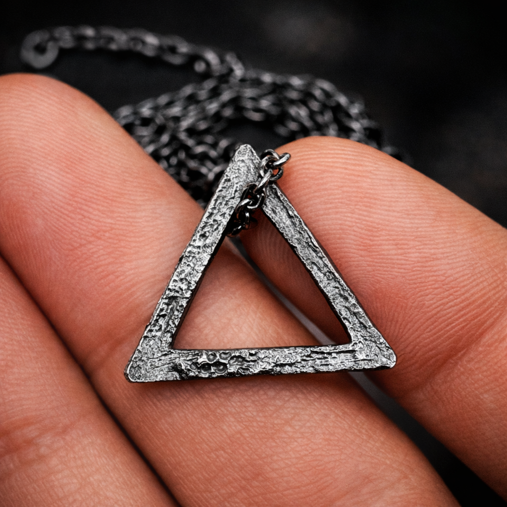Silver triangle pendant on a chain held between fingers
