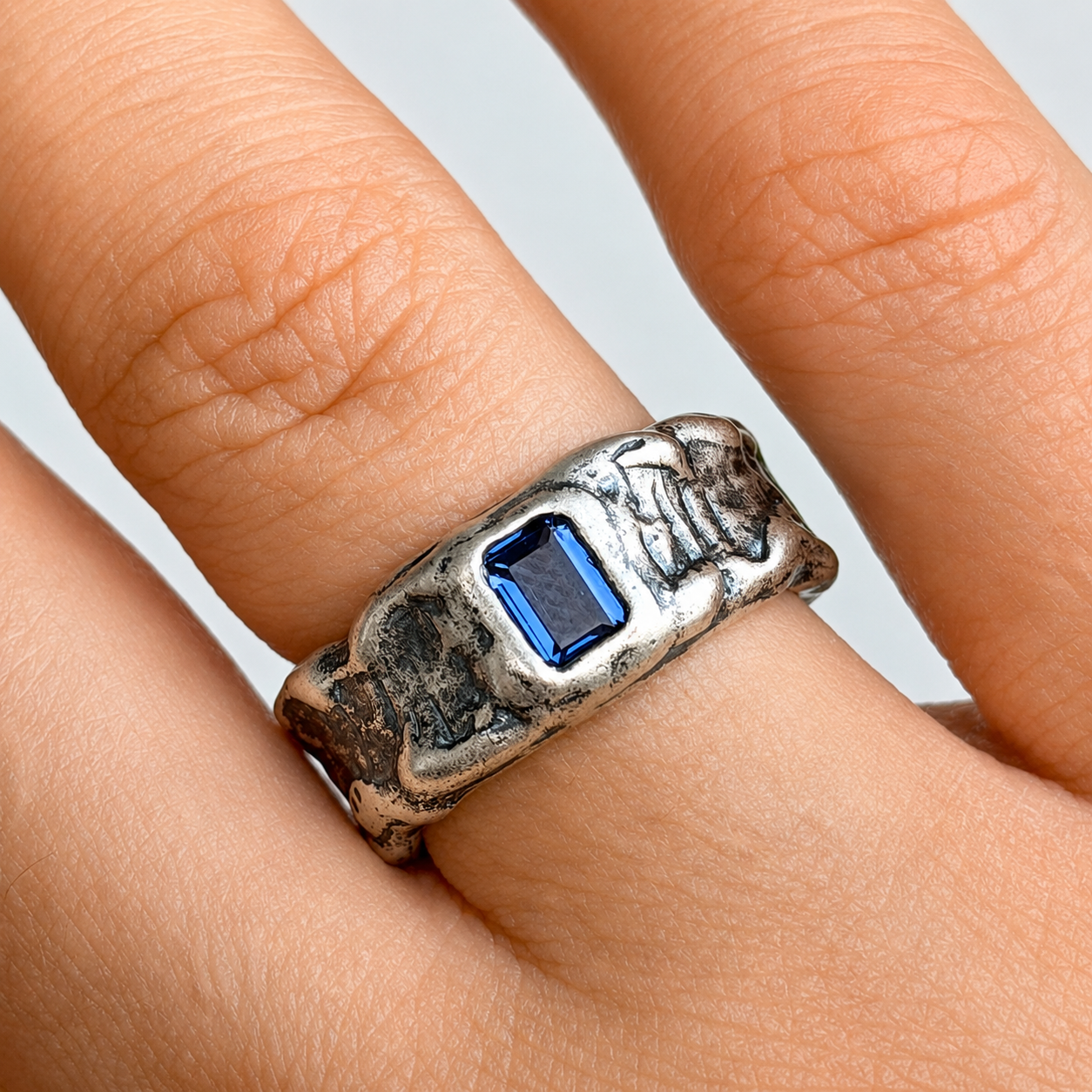 Textured silver ring with blue gemstone.