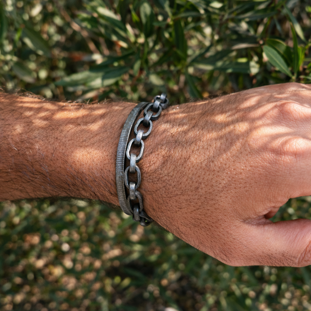 Hand wearing a chain bracelet with a natural background
